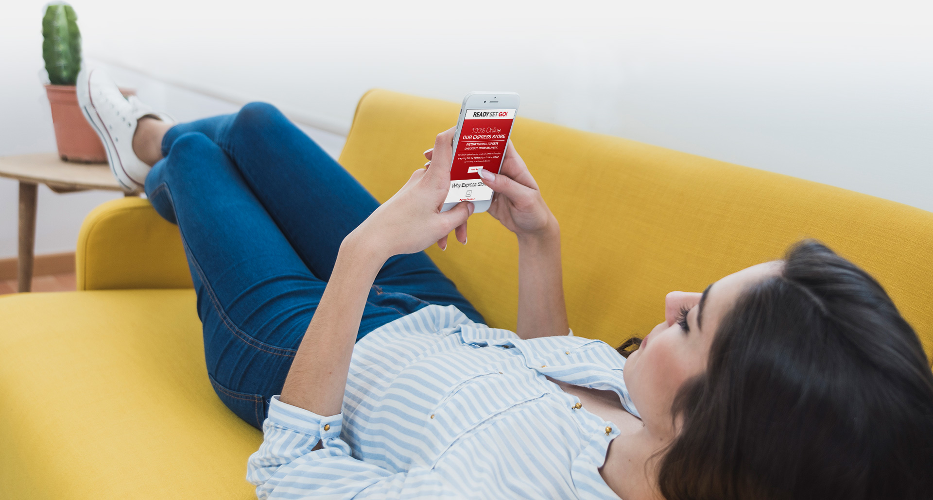 Young woman laying on the couch scrolling through email on phone